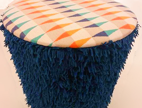 Round upholstered stool with a fringed blue base